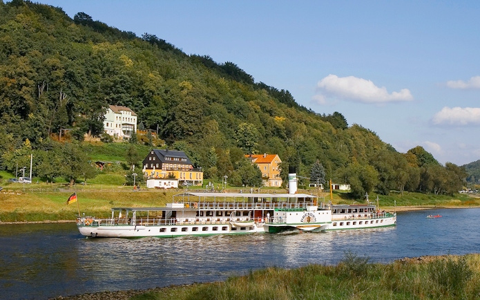 Elbe River cruise ship near Pillnitz Castle, Dresden, with hillside view.