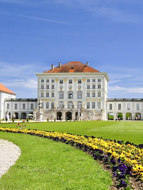 Nymphenburg Palace in Munich with colorful garden flowers in the foreground.
