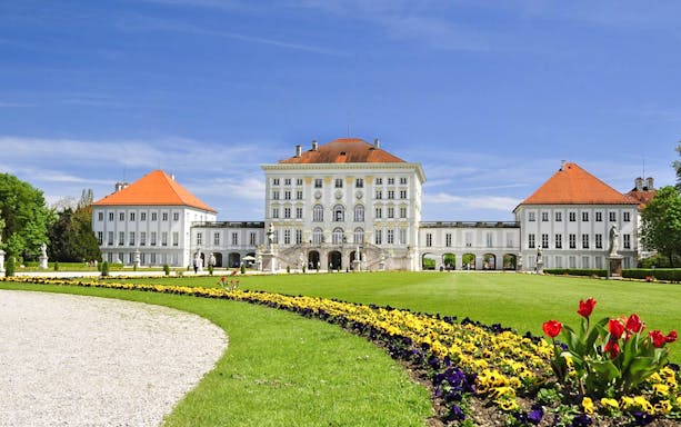 Nymphenburg Palace in Munich with colorful garden flowers in the foreground.