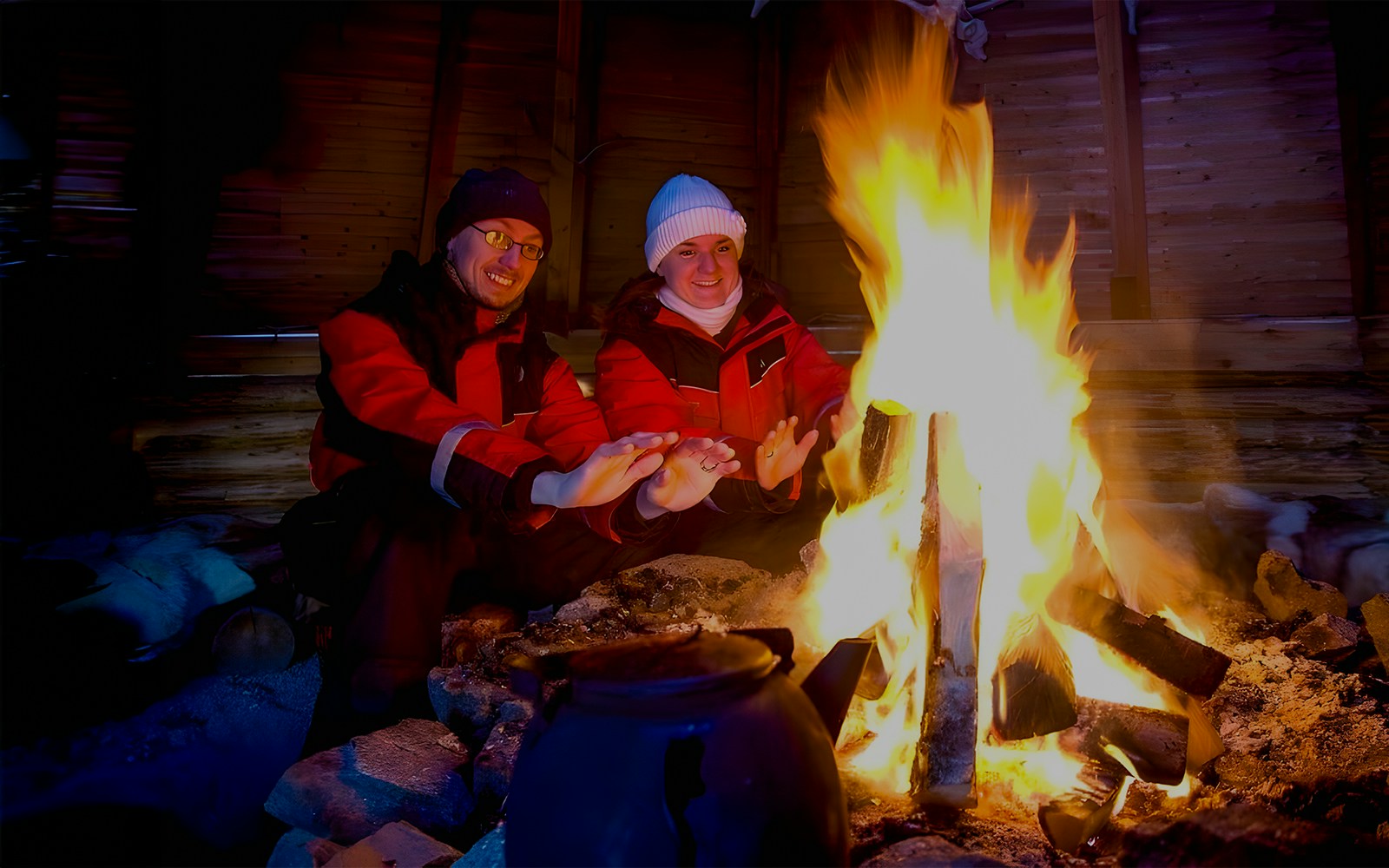 Northern lights with tourists at a campfire.