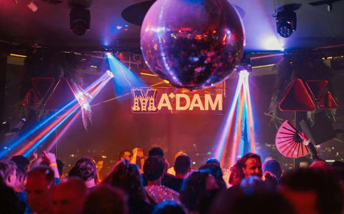 Crowd enjoying nightlife at A'DAM Tower Skybar with disco lights and music.