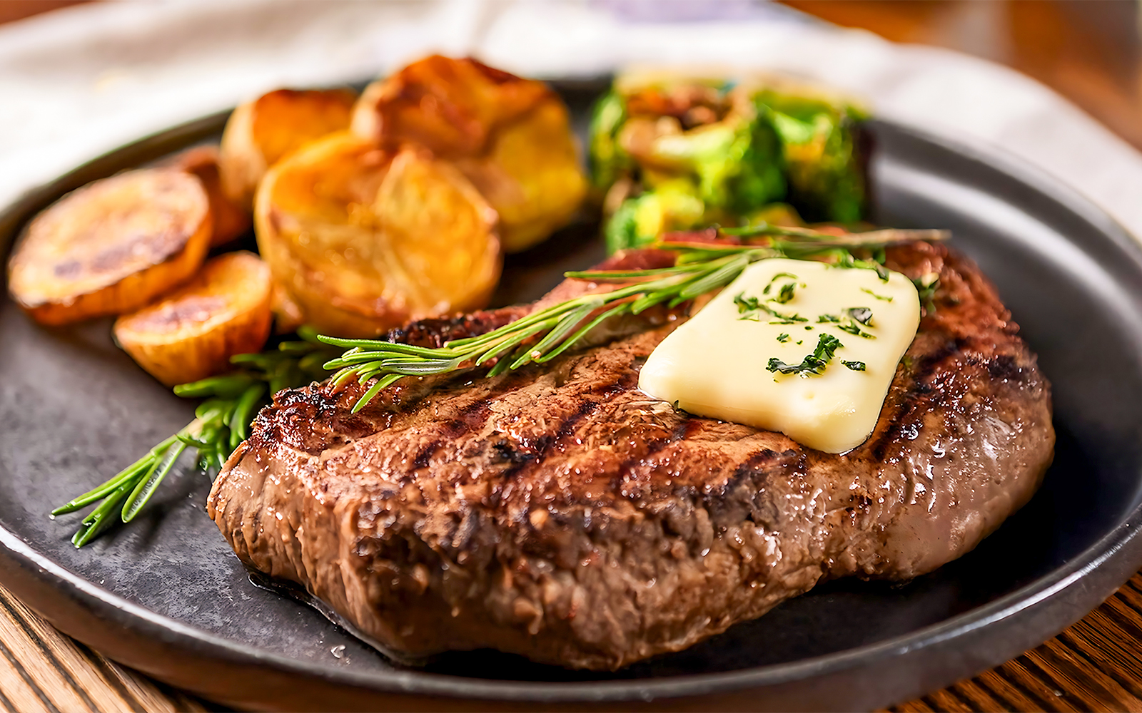 Buttered steak with herbs and potatoes on a plate.