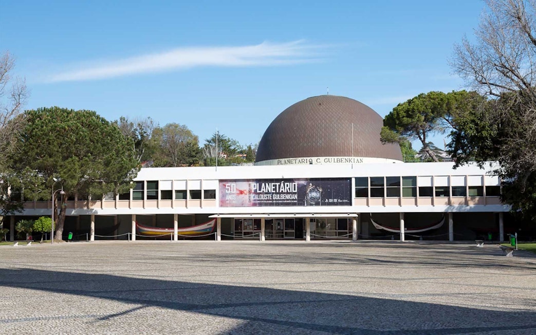 Navy Planetarium entrance in Lisbon with dome and surrounding trees.