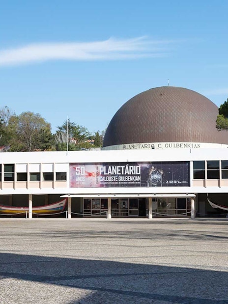 Navy Planetarium entrance in Lisbon with dome and surrounding trees.