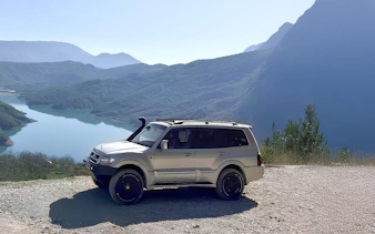 4x4 vehicle parked with Bovilla Lake and mountains in the background during offroad tour from Tirana.