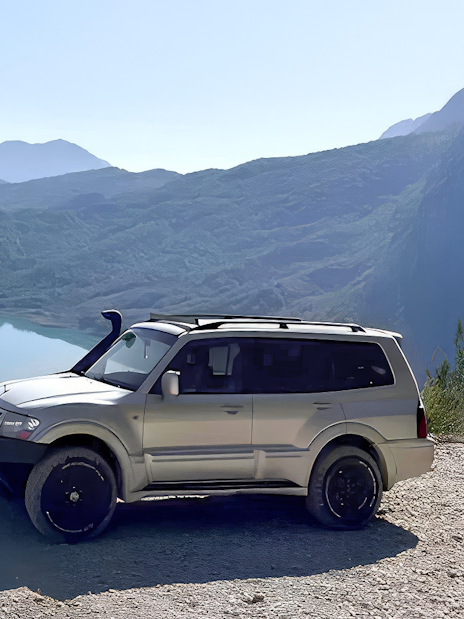 4x4 vehicle parked with Bovilla Lake and mountains in the background during offroad tour from Tirana.