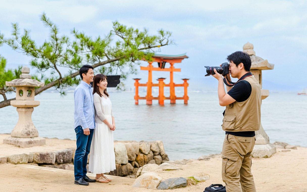 Photographer capturing a couple near the Torii gate at Miyajima, Japan.