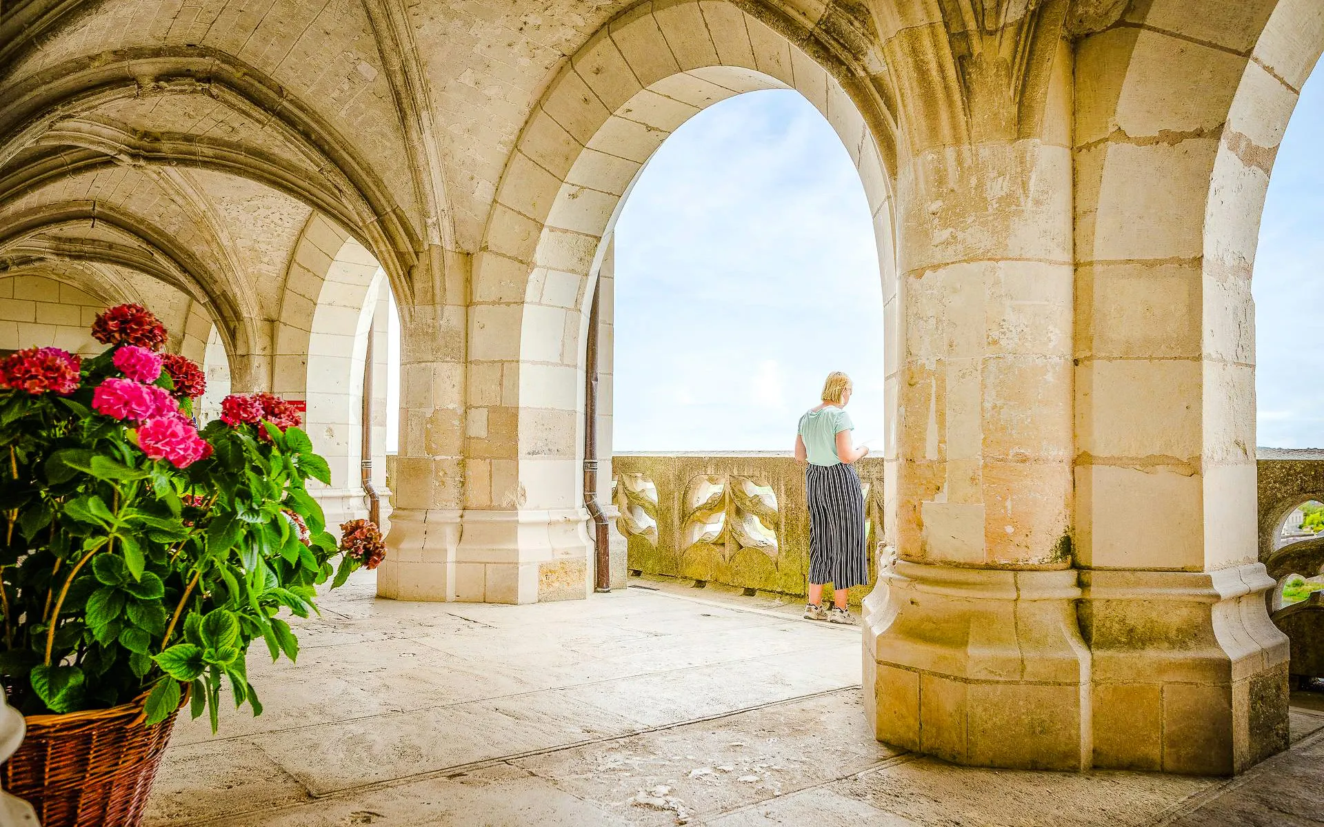 Visitor admiring view from stone arches at Amboise Royal Castle, France.