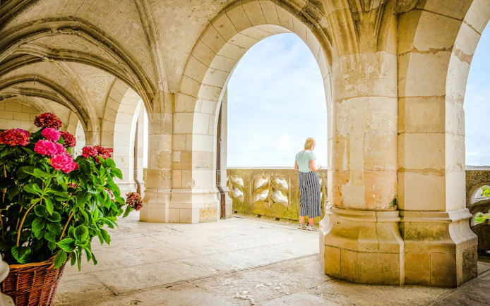 Visitor admiring view from stone arches at Amboise Royal Castle, France.
