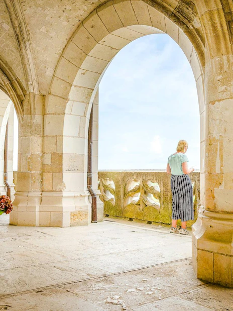 Visitor admiring view from stone arches at Amboise Royal Castle, France.