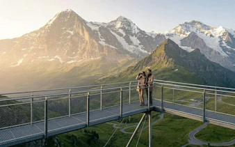 Visitors on a viewing platform overlooking the Swiss Alps in Grindelwald, Switzerland.