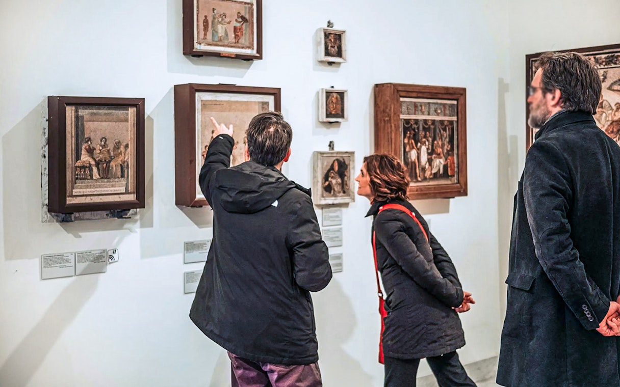 Visitors examining ancient frescoes at Naples National Archaeological Museum.