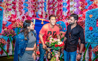 Visitors interacting with a wax figure at Dubai Madame Tussauds, surrounded by colorful flowers.