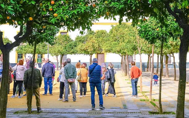 Visitors in the gardens of the Alcazar of Seville during a guided tour.