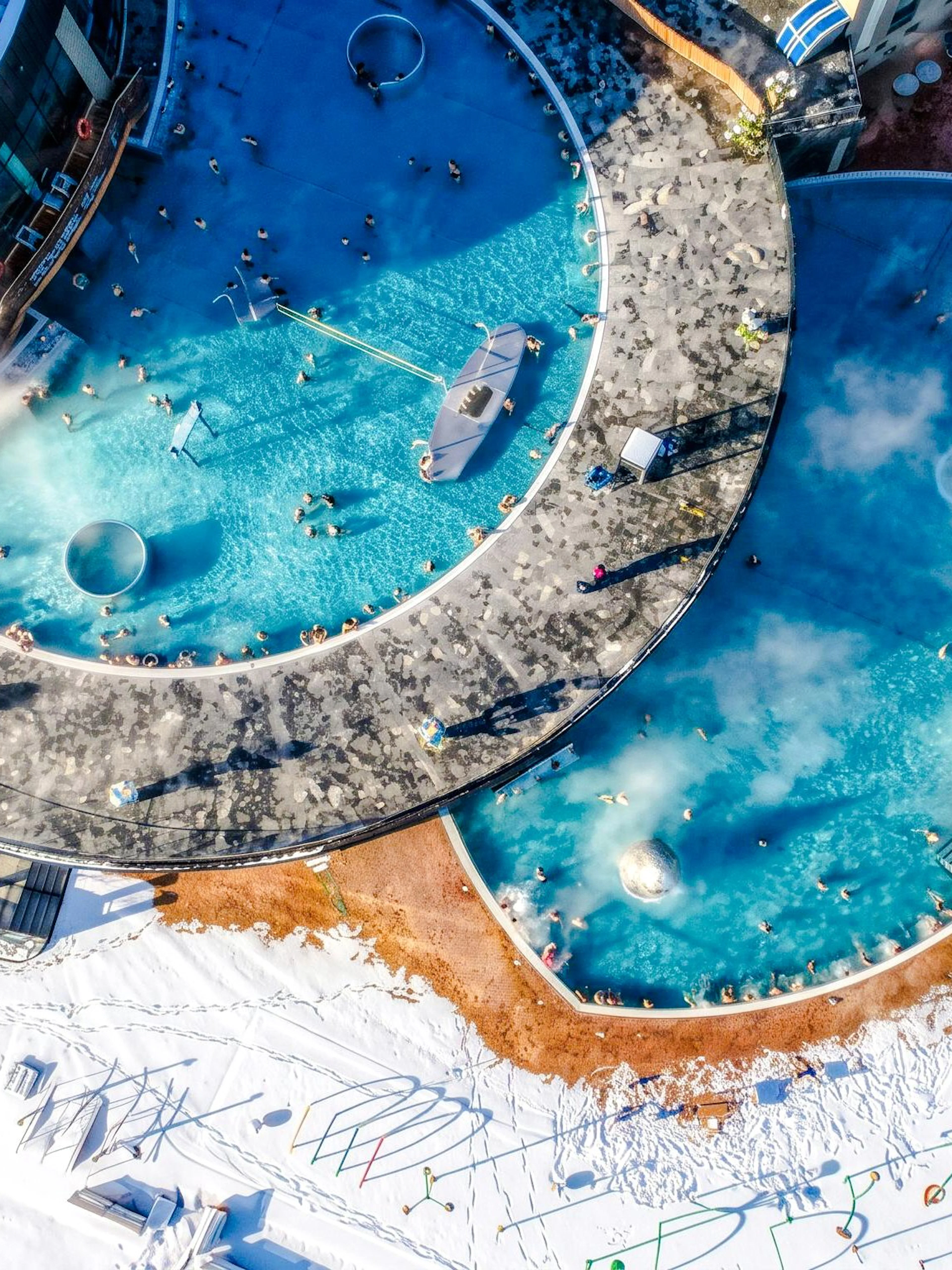 Aerial view of Chocholow Thermal Baths with outdoor pools in snowy landscape.