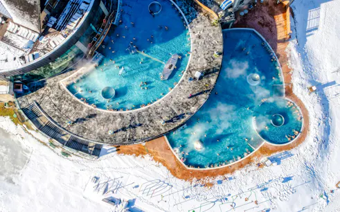 Aerial view of Chocholow Thermal Baths with outdoor pools in snowy landscape.