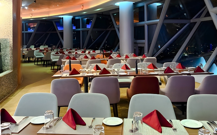 Dining setup at Orbit Revolving Restaurant, KL Tower, Kuala Lumpur, with city skyline view.