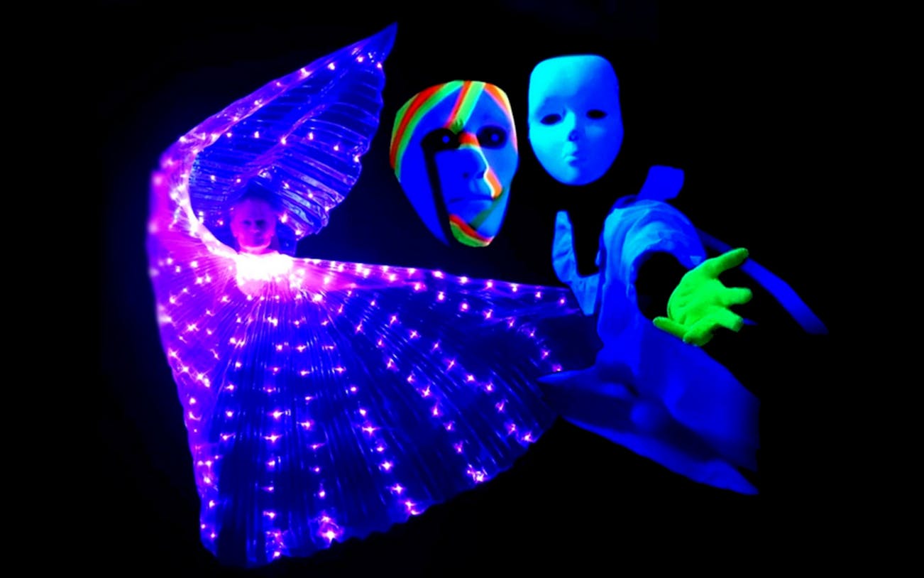 Black light theatre performers with glowing costumes and masks in Prague.