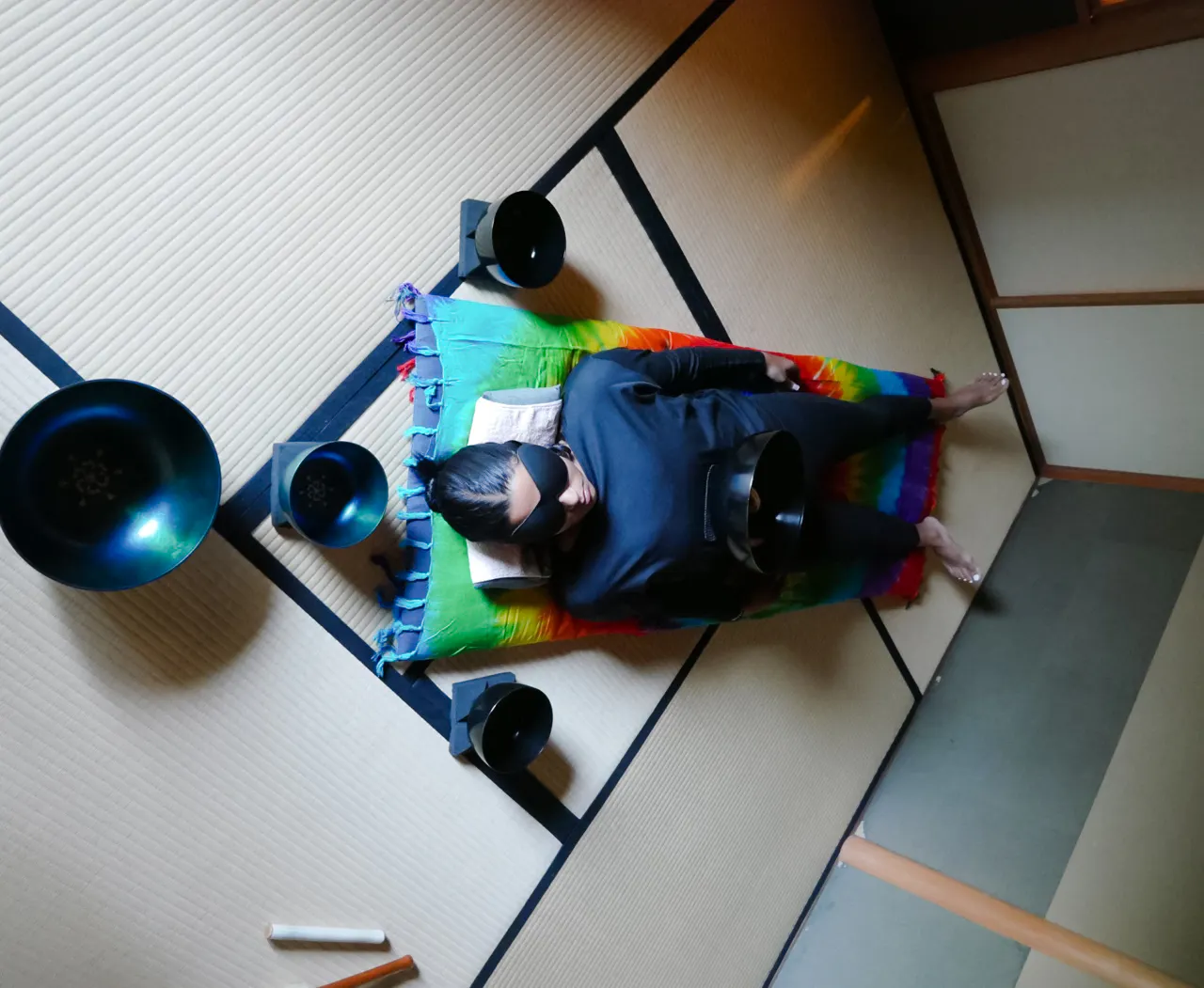 Person lying on a mat with sound bowls in a Kyoto Japanese sound bath session.