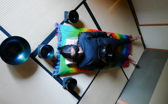 Person lying on a mat with sound bowls in a Kyoto Japanese sound bath session.