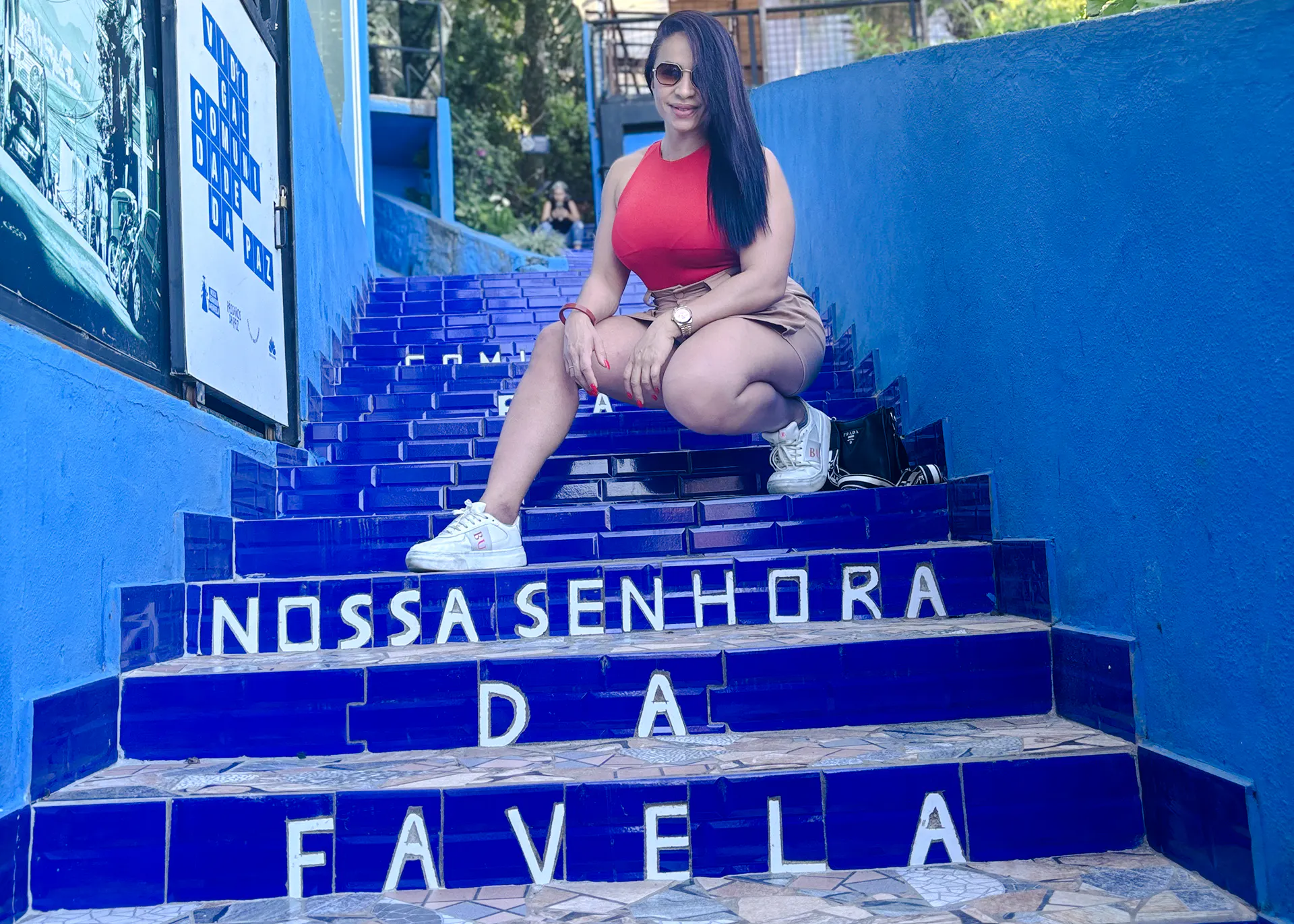Woman sitting on blue tiled steps in Vidigal, Rio de Janeiro.