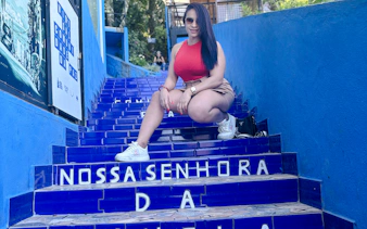 Woman sitting on blue tiled steps in Vidigal, Rio de Janeiro.