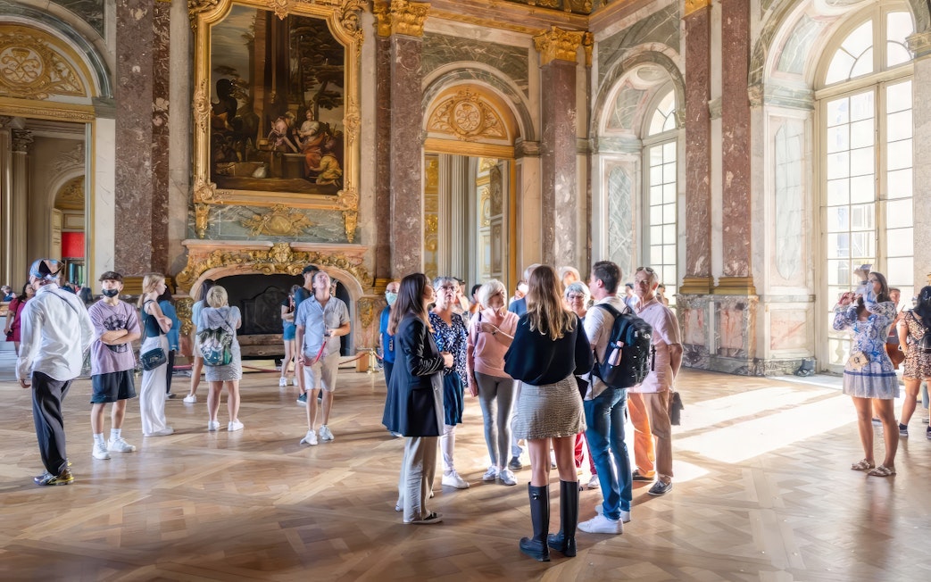 Tour group with guide in Hercules Drawing Room, Versailles Palace, France.