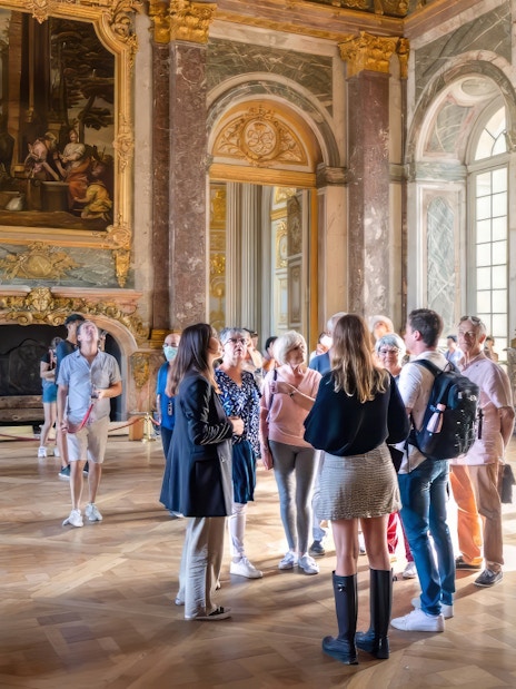 Tour group with guide in Hercules Drawing Room, Versailles Palace, France.