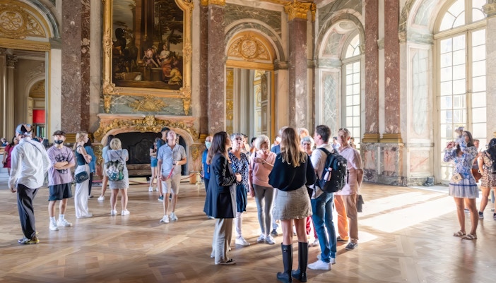 Tour group with guide in Hercules Drawing Room, Versailles Palace, France.
