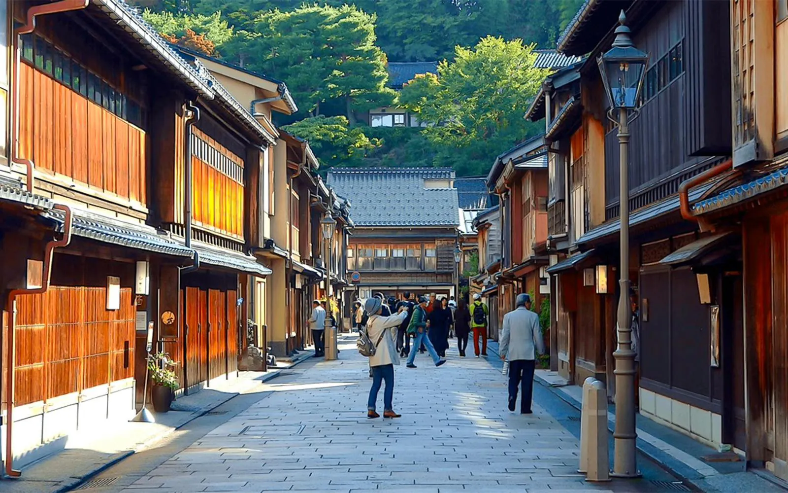 Traditional street in Kanazawa with wooden buildings and tourists exploring.