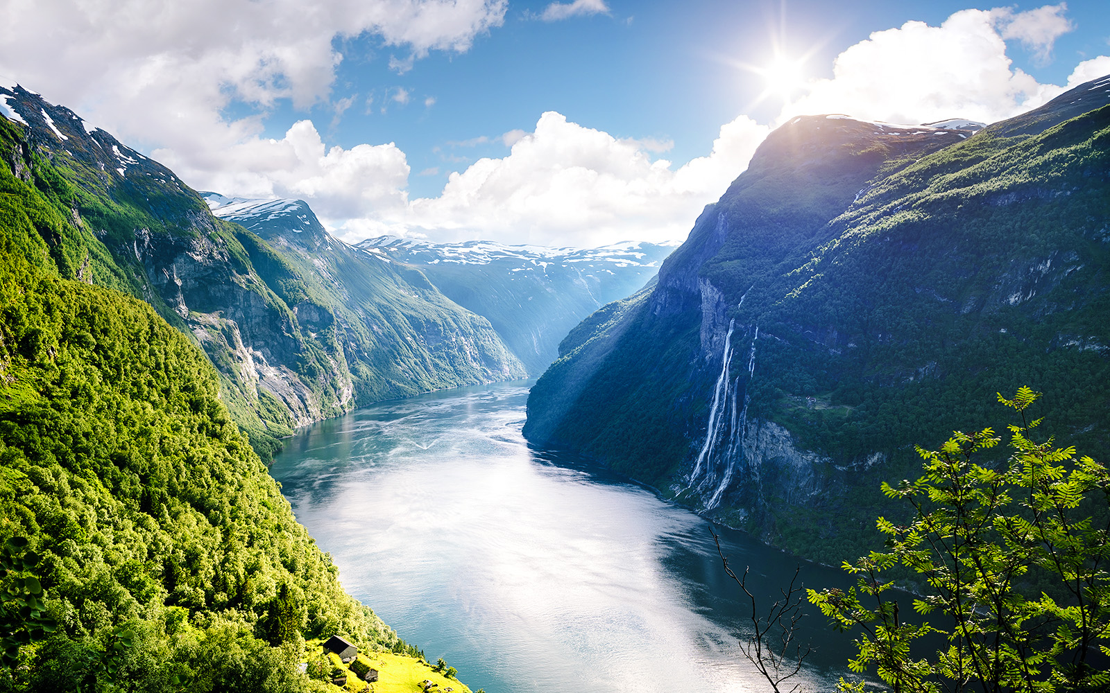 Geirangerfjord with Seven Sisters waterfall in Norway, surrounded by lush green mountains.