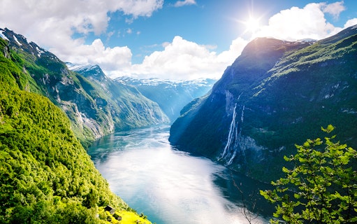 Geirangerfjord with Seven Sisters waterfall in Norway, surrounded by lush green mountains.