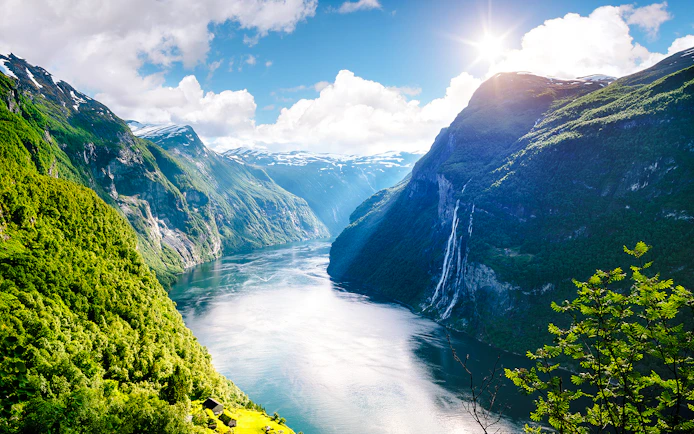 Geirangerfjord with Seven Sisters waterfall in Norway, surrounded by lush green mountains.