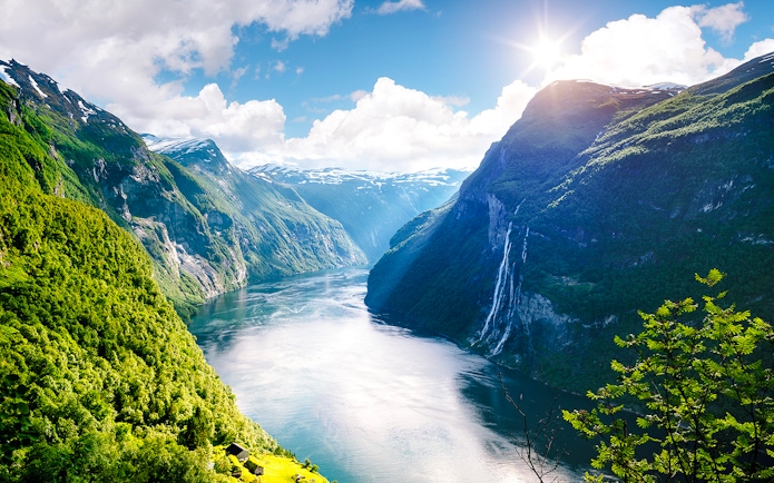 Geirangerfjord with Seven Sisters waterfall in Norway, surrounded by lush green mountains.