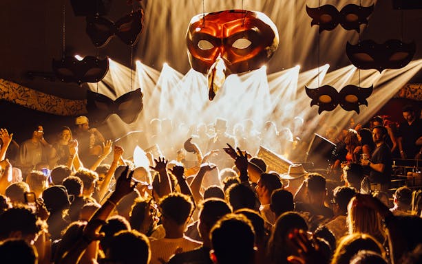 DJ performing at Club Chinois with crowd and masks, Ibiza.