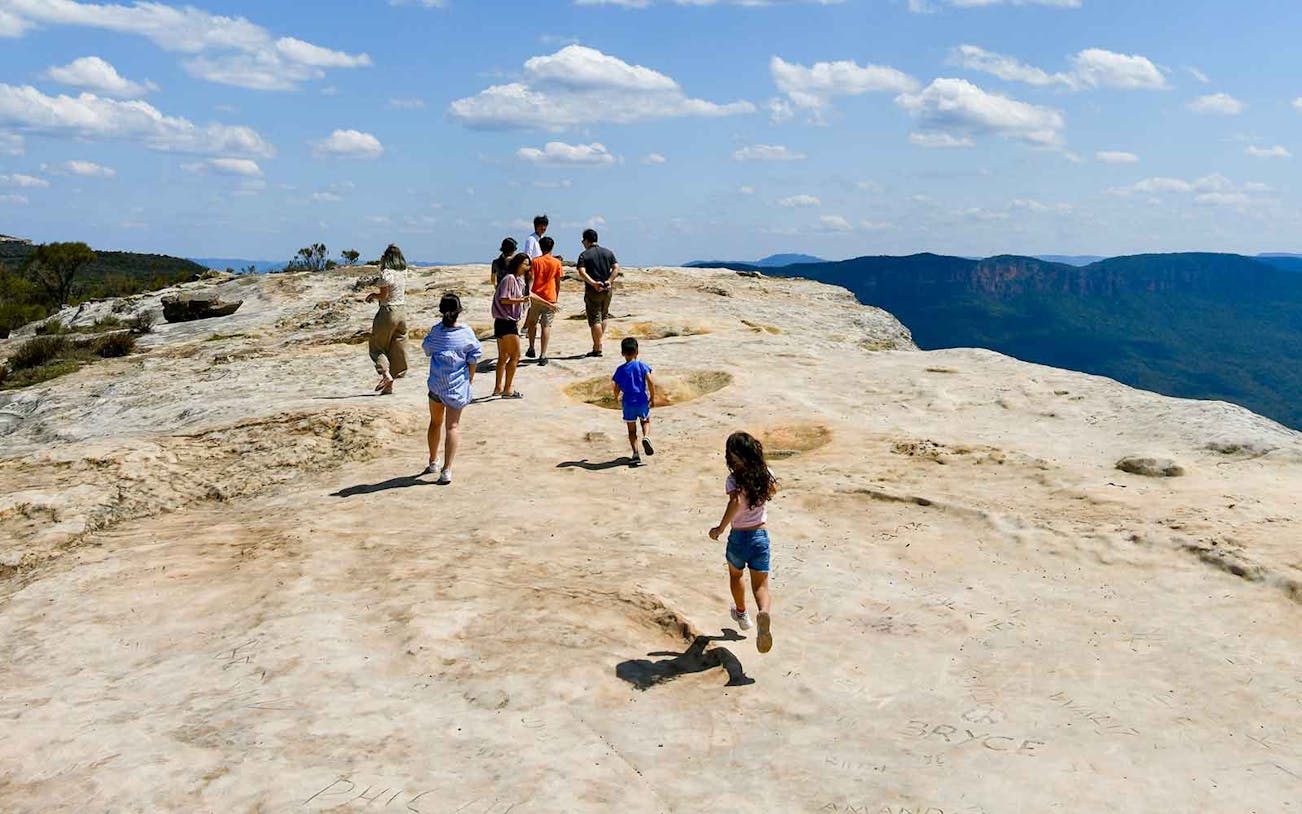 People walking on Lincoln's Rock at Wentworth Falls with scenic views.
