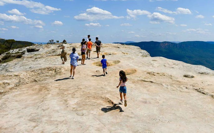 People walking on Lincoln's Rock at Wentworth Falls with scenic views.