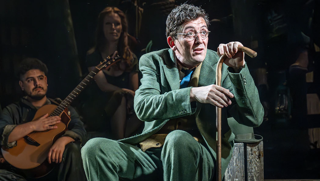Actor in green suit with cane on stage during "The Curious Case of Benjamin Button - The Musical.
