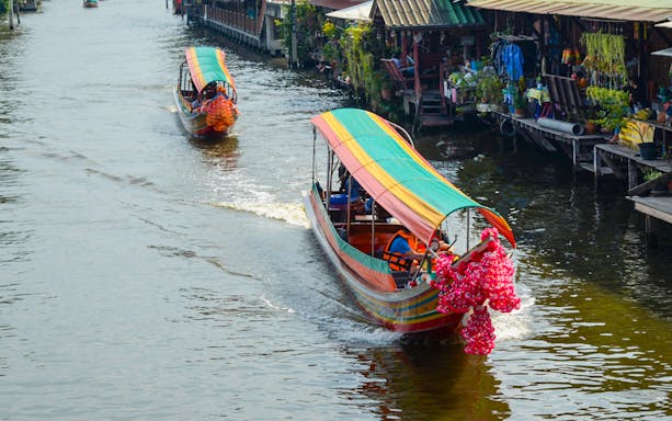 Long-tail boats navigating Bangkok Yai Canal with vibrant decorations.