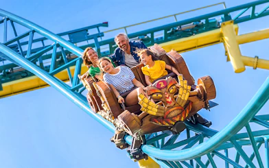 Tourists enjoying Tiki Trail ride at Walibi Belgium, surrounded by vibrant coaster tracks.