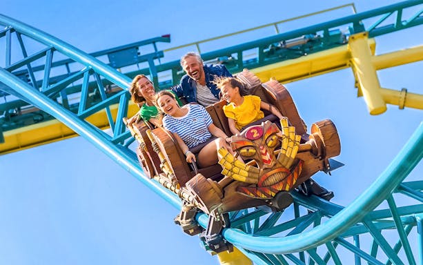 Tourists enjoying Tiki Trail ride at Walibi Belgium, surrounded by vibrant coaster tracks.
