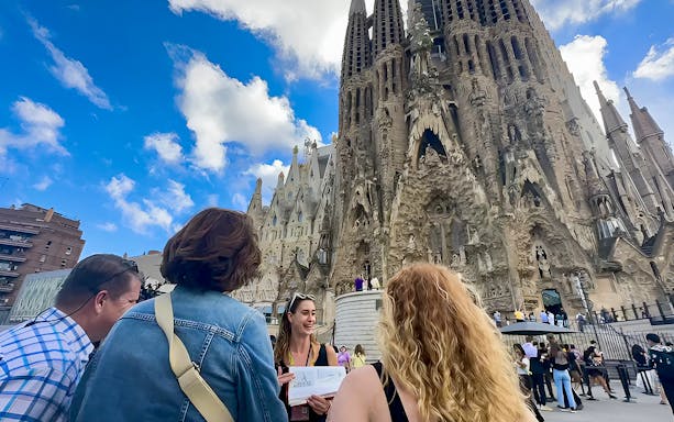 Tour group outside Sagrada Familia in Barcelona with guide holding a sign.