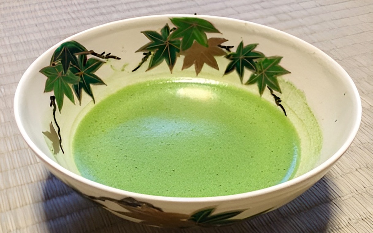 Ceramic bowl with matcha tea and leaf design, Kyoto tea ceremony.