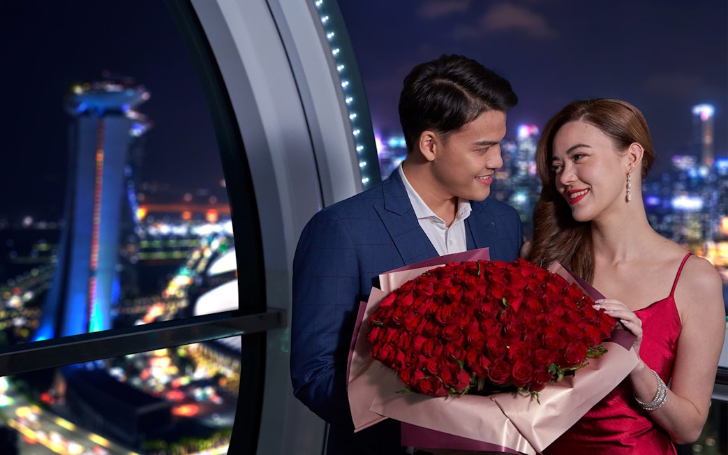 Couple enjoying Singapore Flyer Sky Dining with city skyline in background.