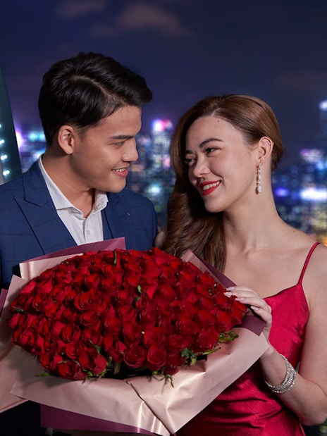 Couple enjoying Singapore Flyer Sky Dining with city skyline in background.