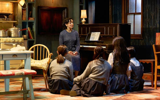 Woman speaking to children in a cozy room with a piano, set in The Hills of California.