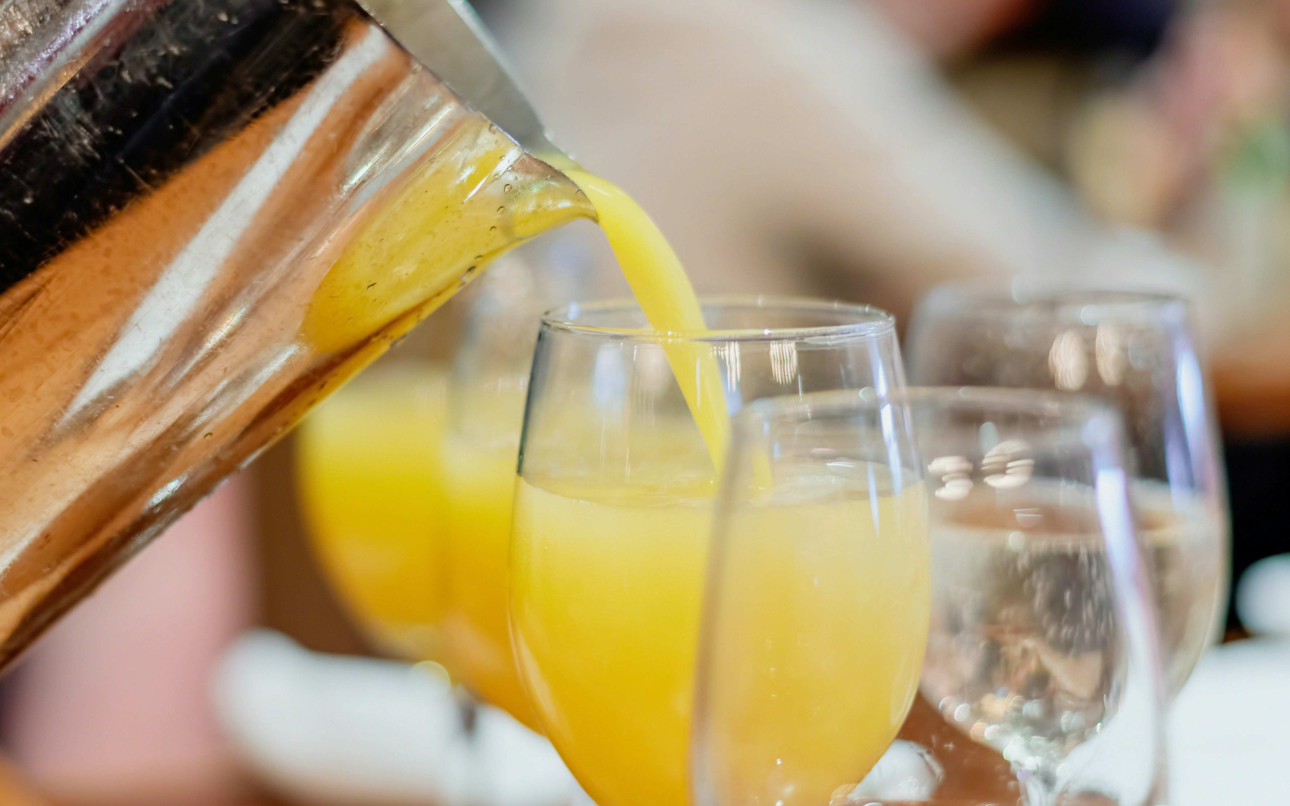 Pouring orange juice into glasses for mimosas.