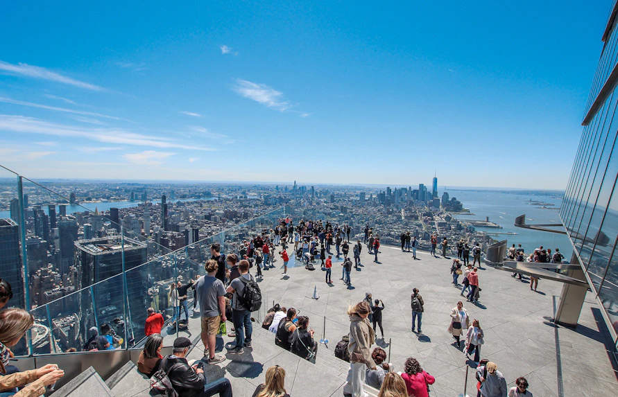 Visitors on The Edge NYC observation deck overlooking Manhattan skyline.