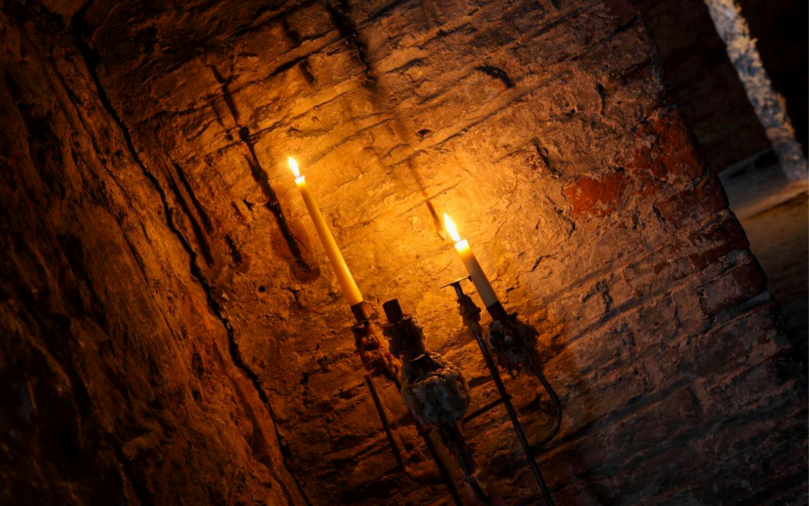 Candles illuminating a stone wall in Edinburgh's haunted underground.
