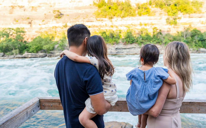 Family enjoying the view of white water rapids from a wooden railing.